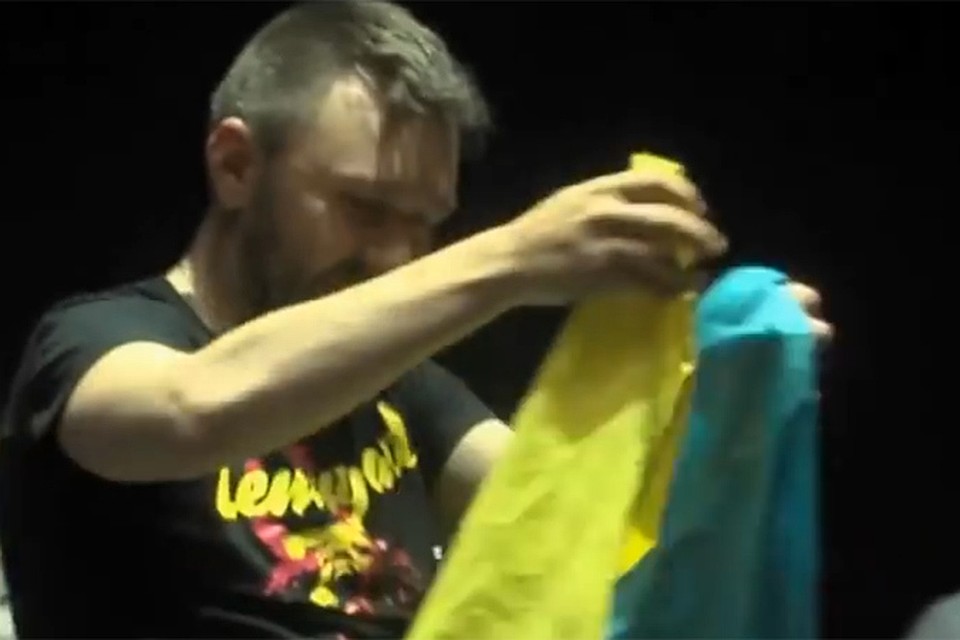 На коротком видео запечатлен момент, когда лидер группы Сергей Шнуров из желания не обидеть одного из зрителей все-таки берет в руки передаваемый ему украинский флаг