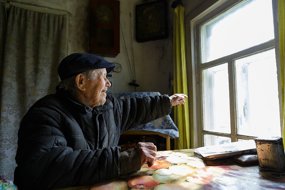 Евгений Васильевич Попов, дома сидя у окна, показывает в даль: «Вооот там, вниз по реке - деревня Гам». В ту деревню в социально-реабилитационный центр для несовершеннолетних он отдал свой капитал Фото: Наталия БЕШКАРЕВА