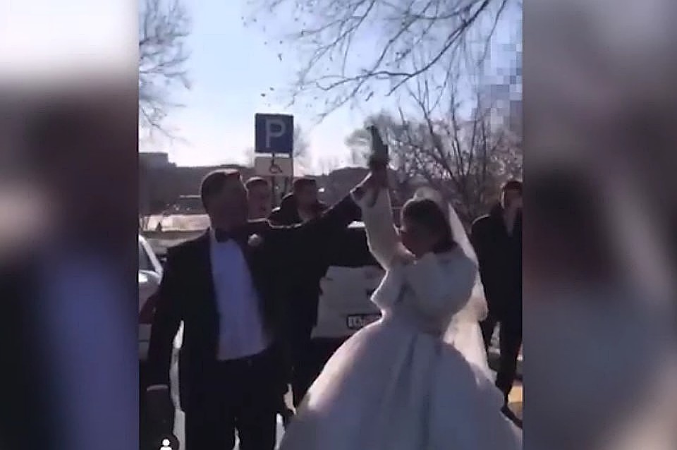 Кадр с видео: жених сам опробовал автомат, а потом помог невесте выстрелить из пистолета