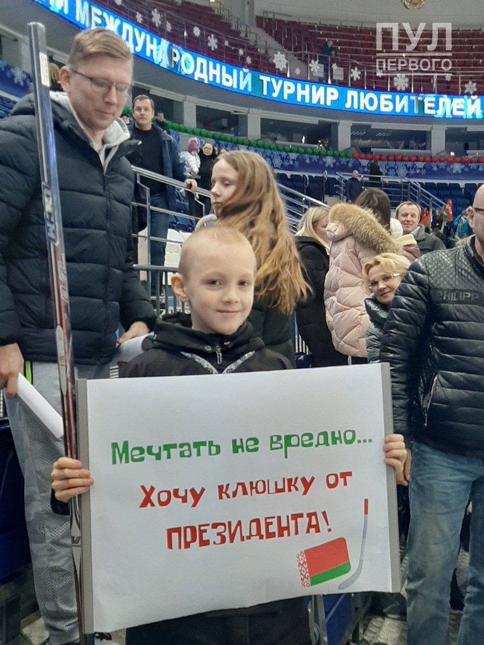Мальчик с тем самым плакатом и клюшкой президента. Фото: Телеграм-канал Пул Первого (t.me/pul_1)