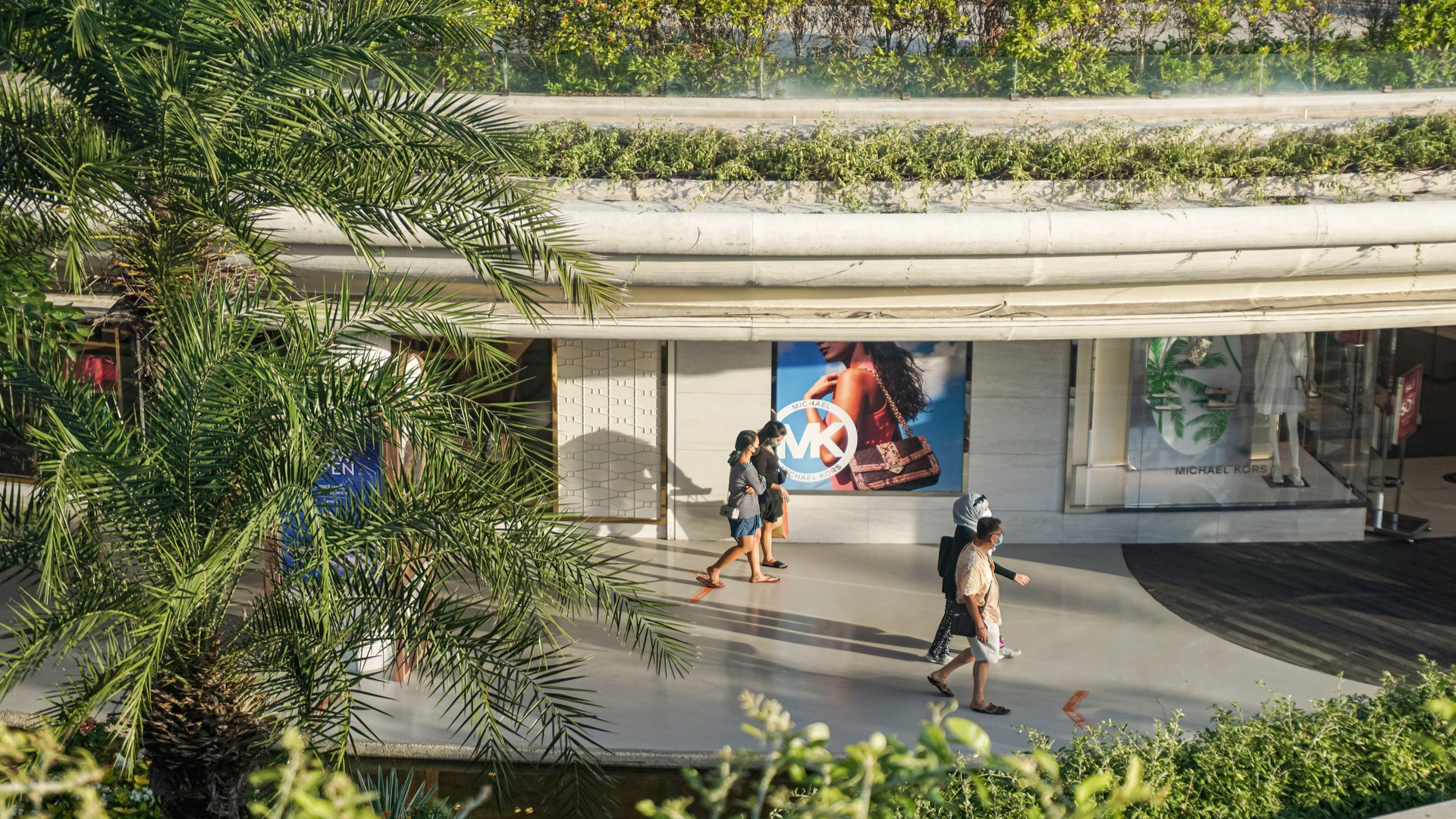 Посетители прогуливаются по коридору торгового центра Bali Beachwalk.
