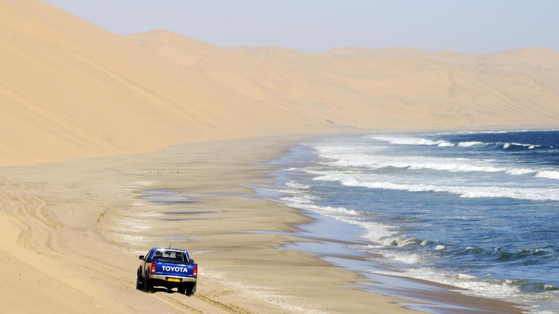 Внедорожник едет по Сэндвич-Харбору, Намибия.